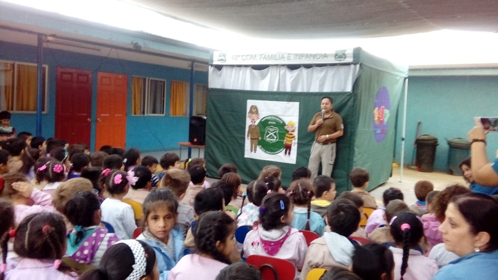 Un carabinero de la 48ª Comisaría de Familia e Infancia da una charla a los niños sentados en el patio.